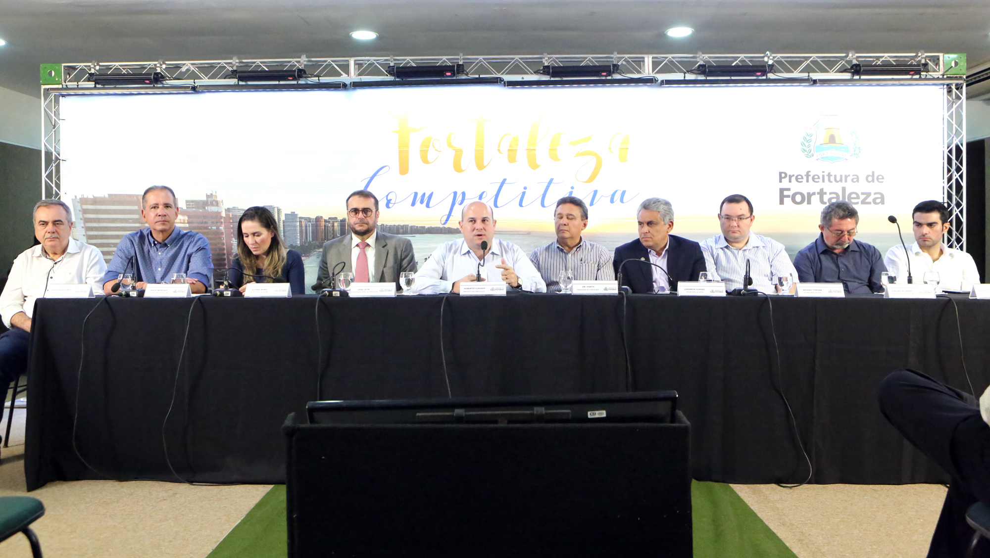mesa de auditório com várias pessoas sentadas